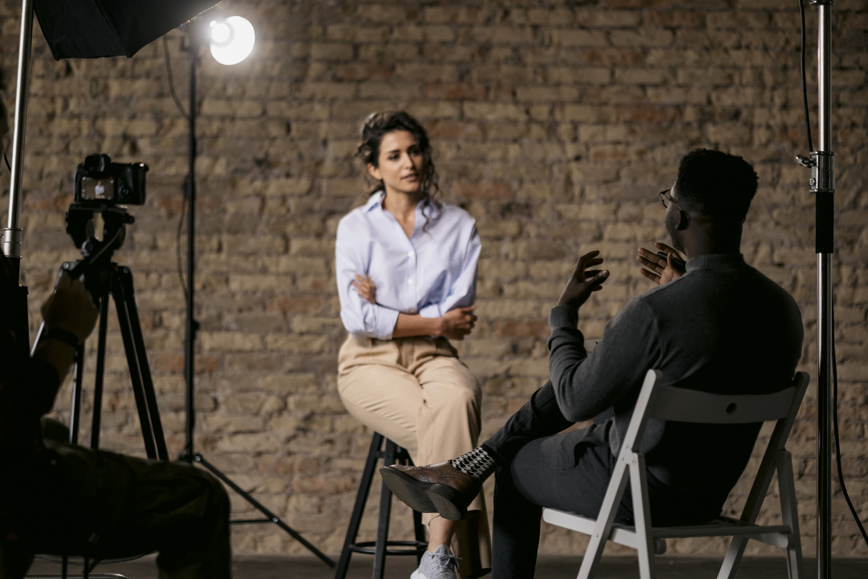 Journalist interviewing a young woman in a studio